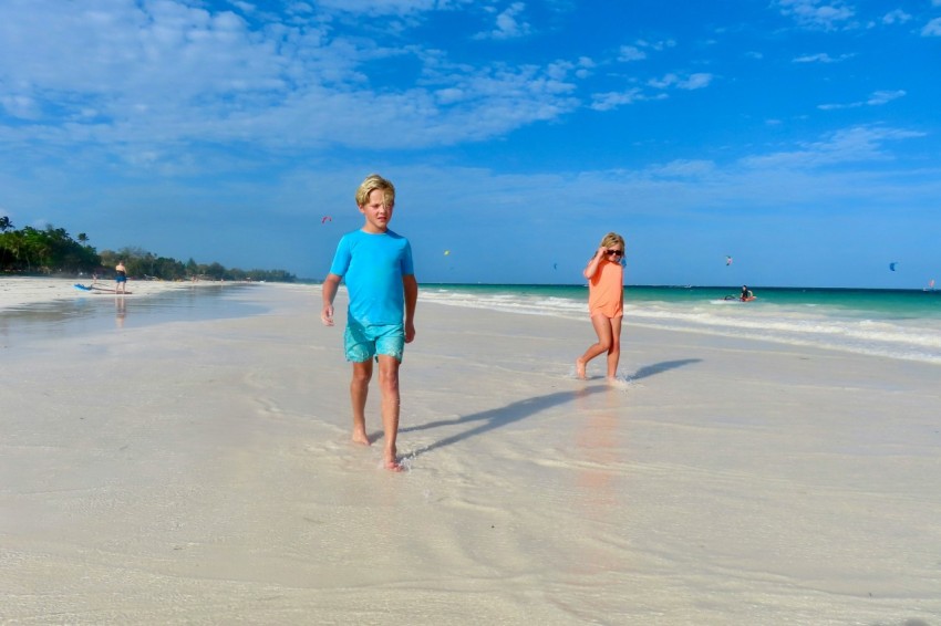 a boy and a girl are walking on the beach