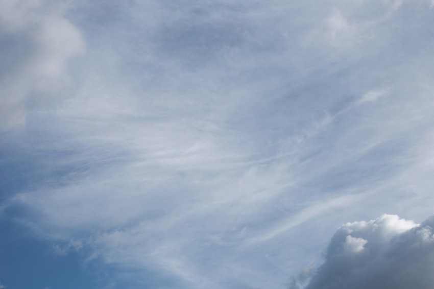 a plane flying through a cloudy blue sky