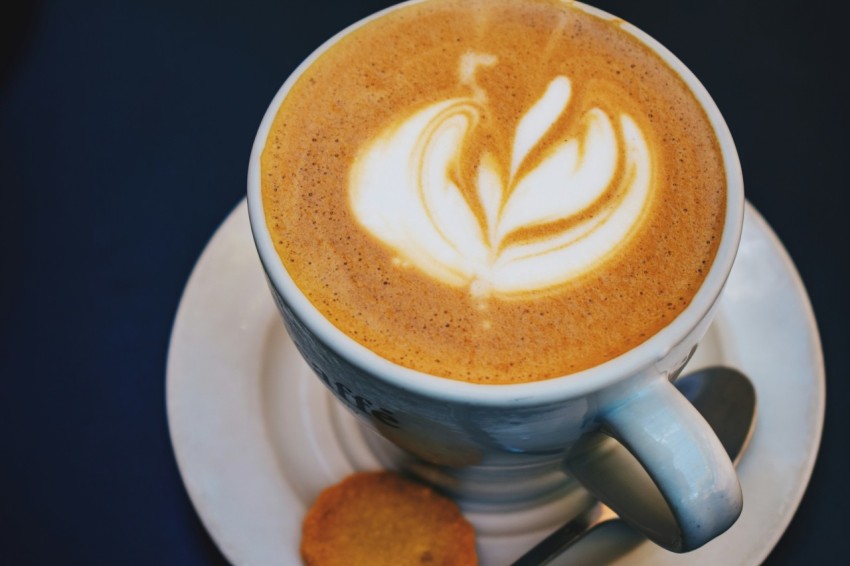 a cup of cappuccino on a saucer with a spoon