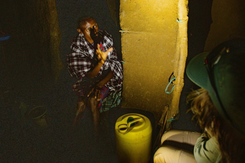 a man sitting next to a yellow trash can