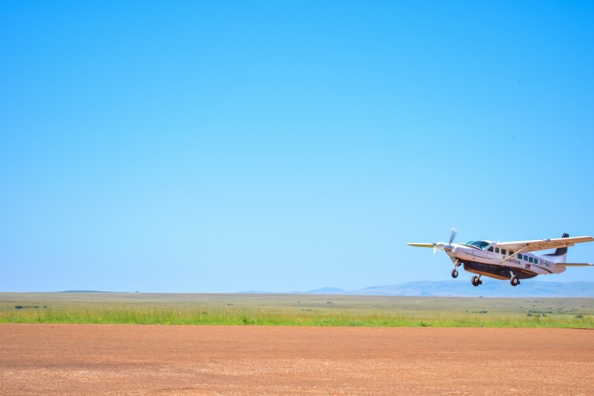 a small plane flying low over a dirt field