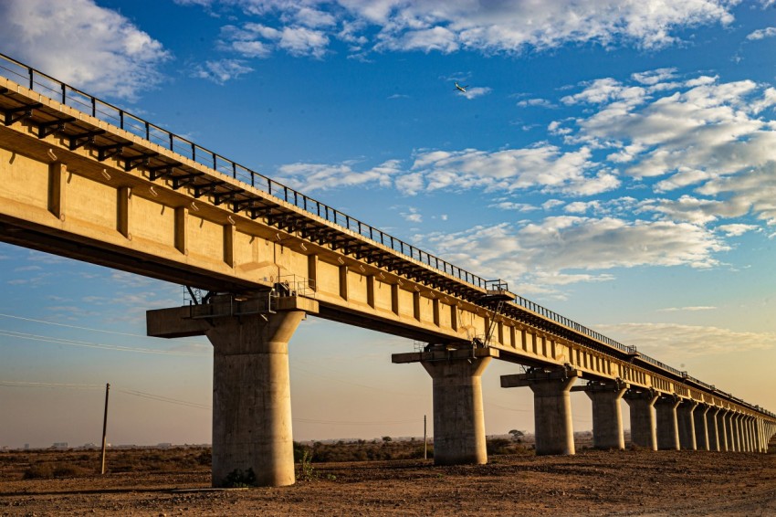 a large bridge over a dirt field under a blue sky