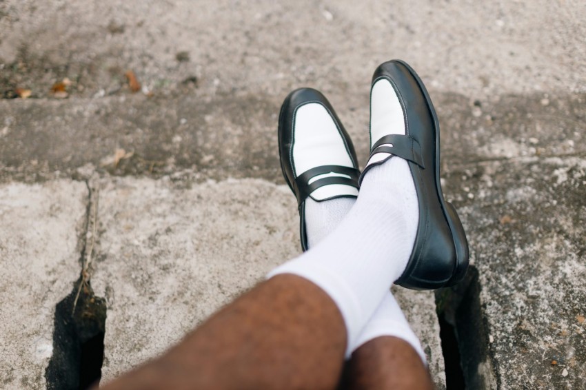 a person wearing white socks and black shoes