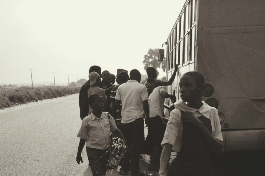 grayscale photography of people standing near bus