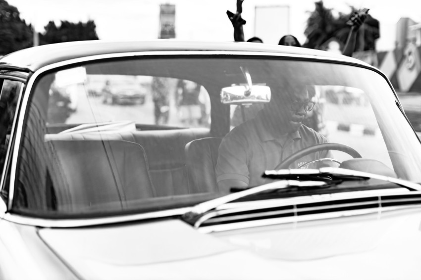 a black and white photo of a woman driving a car