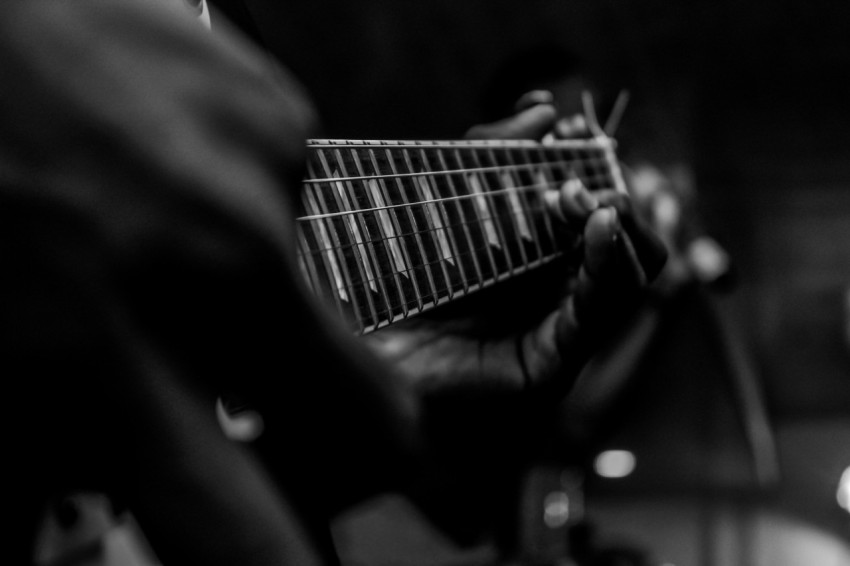 person playing guitar in grayscale photography