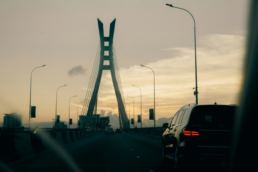 a car driving on a road near a tall bridge