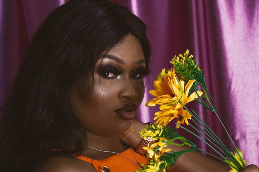 woman in orange tank top holding yellow flowers