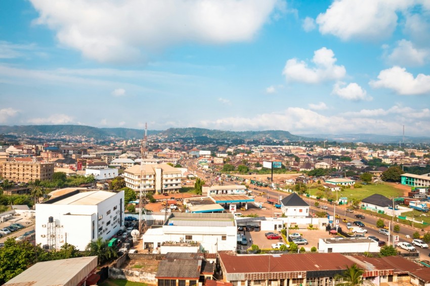 aerial photography of houses and buildings on green field viewing mountain under white and blue sky