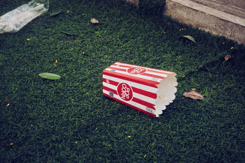 a red and white box sitting on top of a lush green field