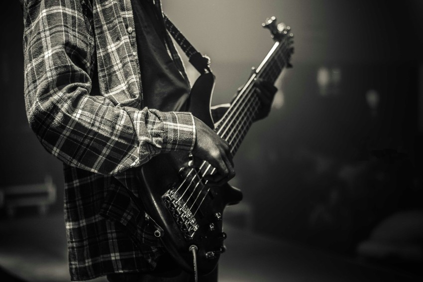 grayscale photo of man playing electric guitar fjvS