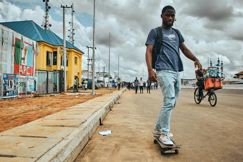 man in blue denim jeans and black t shirt walking on sidewalk during daytime