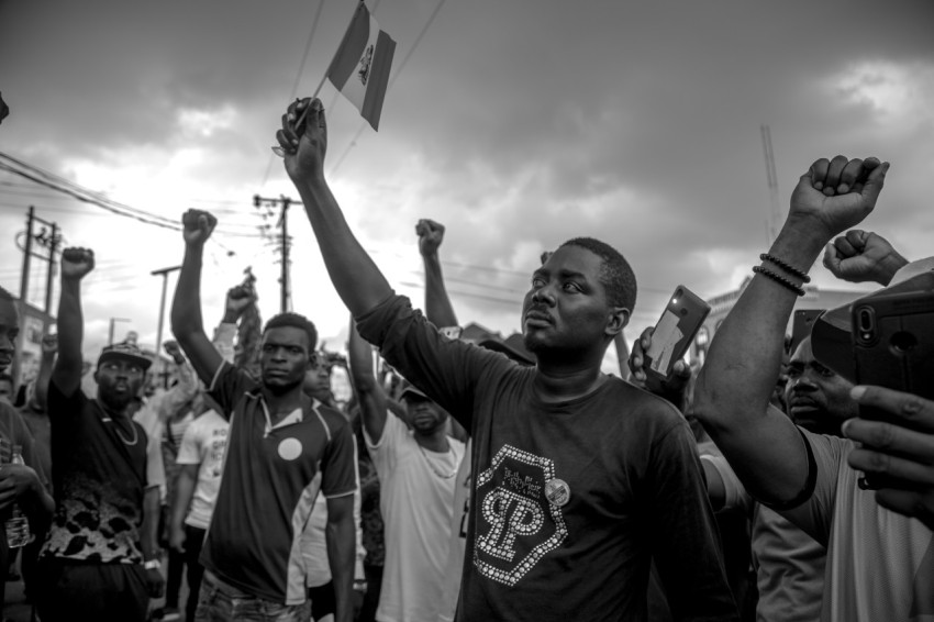 grayscale photo of man in crew neck t shirt raising his hands