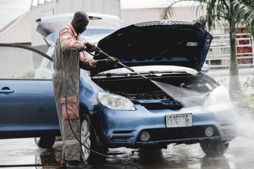 man in gray coat standing beside blue car during daytime