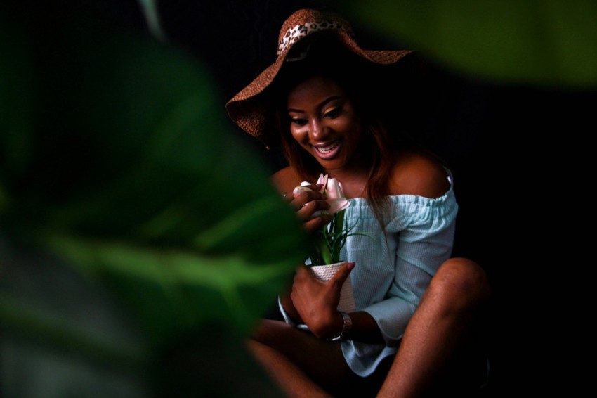 woman in white tank top and brown hat sitting on green grass