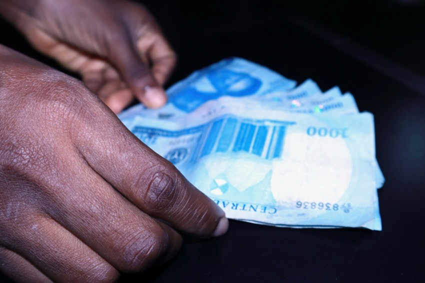 a persons hand reaching for a piece of paper money C8N