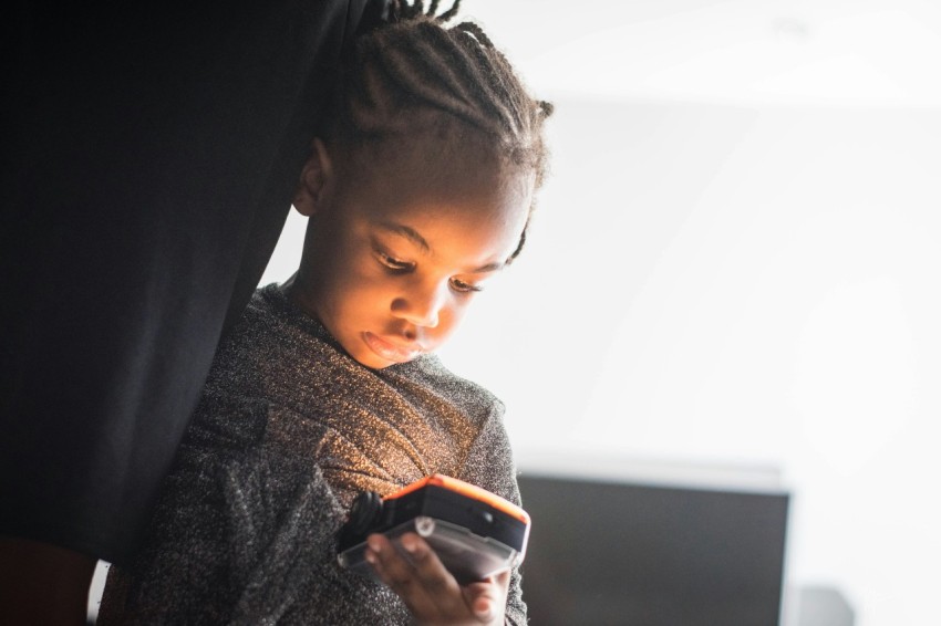 boy in brown and gray sweater holding black smartphone