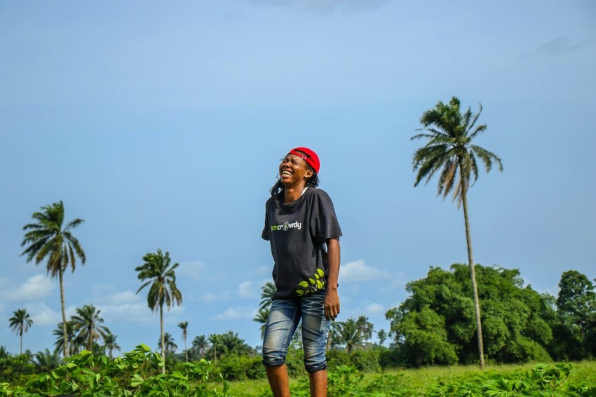 man in black crew neck t shirt and blue denim shorts standing near green palm tree