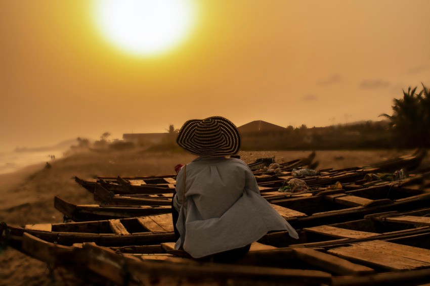 person in white robe and brown hat sitting on brown wooden bench during daytime tOshpNl