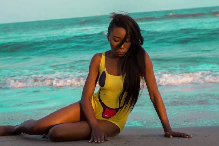 woman in yellow and black one piece swimsuit standing on beach during daytime ql