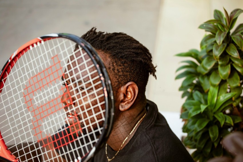 man in black jacket holding red and black tennis racket