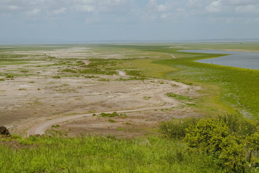 a wide open field with a body of water in the distance