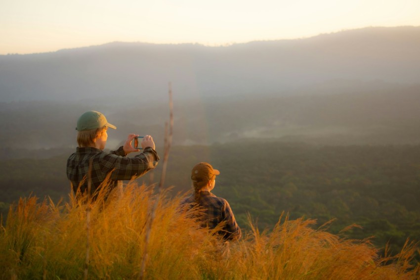 a couple of people standing on top of a lush green hillside