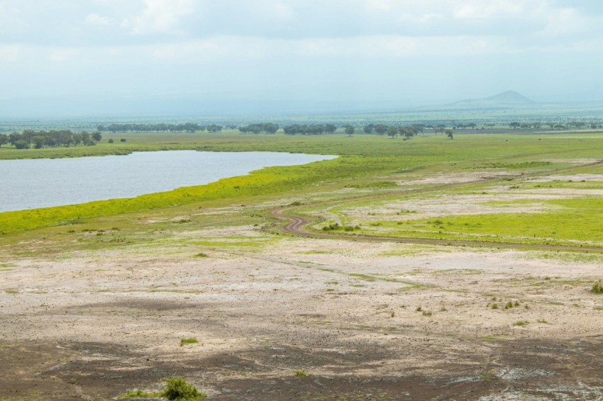 a large body of water sitting next to a lush green field