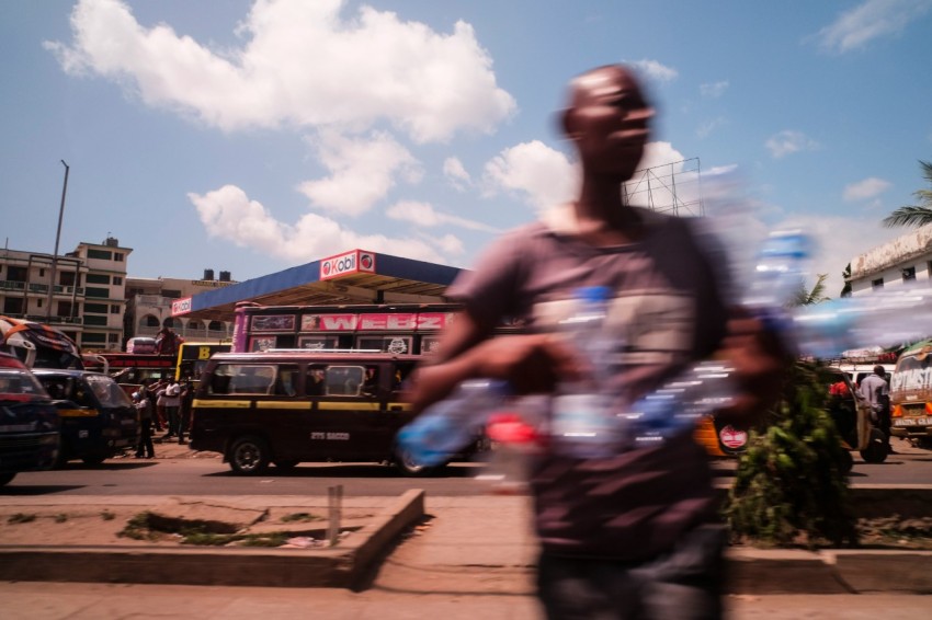 man holds empty water bottles while crossing the street