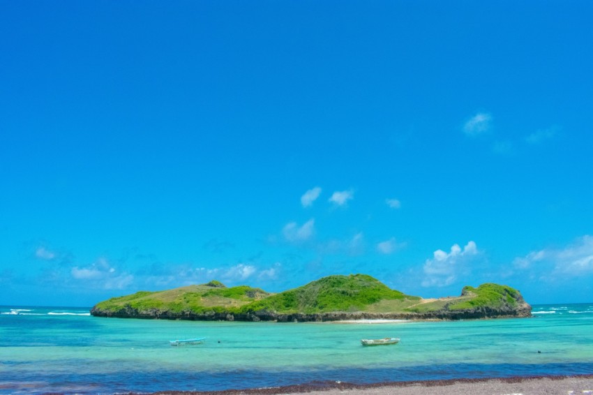 green island on blue sea under blue sky during daytime