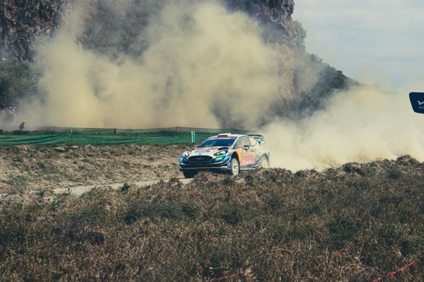 a car driving down a dirt road with a lot of smoke coming out of it