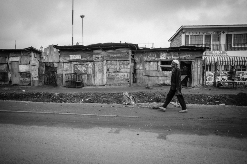 grayscale photo of man walking on road during daytime