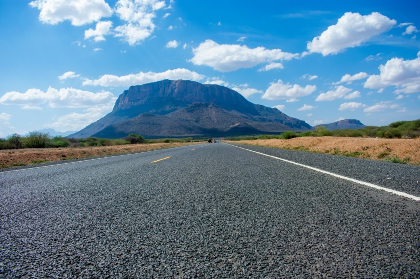 gray asphalt road near green mountains under blue sky during daytime