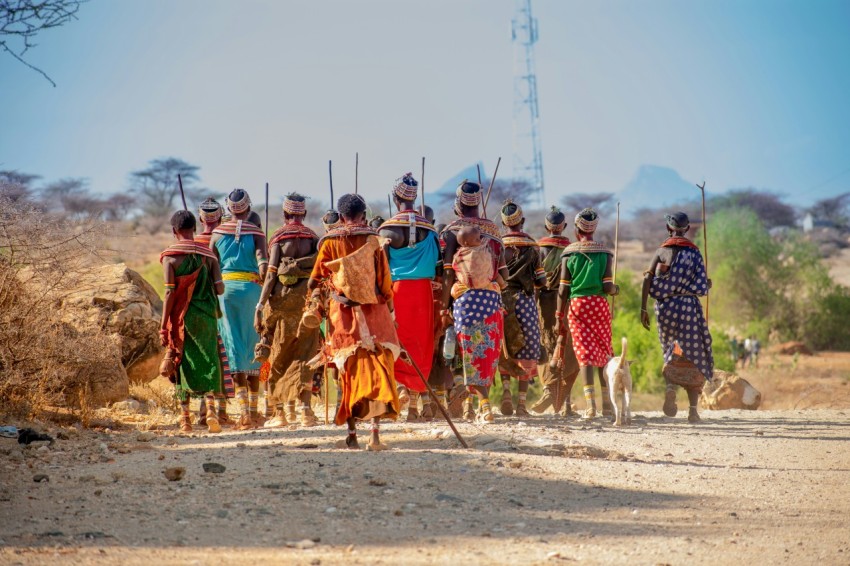 people in orange and yellow traditional dress walking on brown sand during daytime