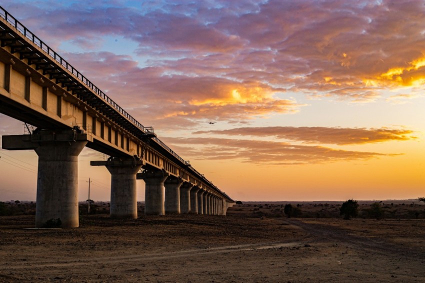 the sun is setting behind a bridge over a dirt road m1lrQC_b