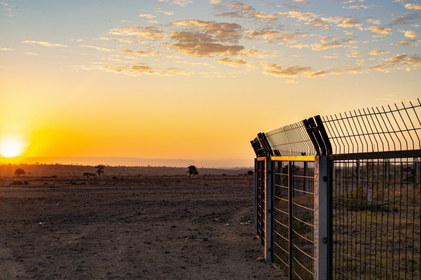 the sun is setting behind a fence in the desert 37QpL