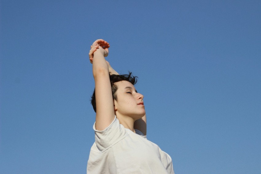 a woman reaching up into the air to catch a frisbee