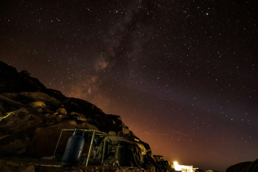 the night sky is filled with stars above a rocky area