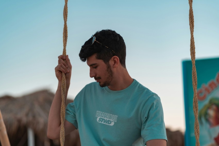 man in blue crew neck t shirt holding brown rope during daytime