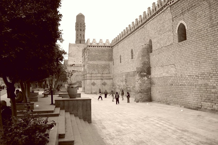 a black and white photo of people walking in a courtyard