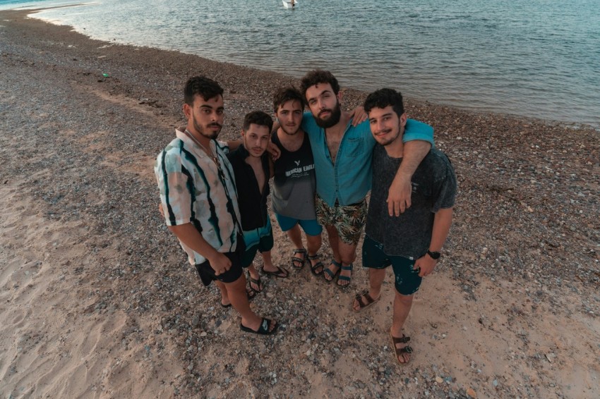 group of people standing on brown sand near body of water during daytime