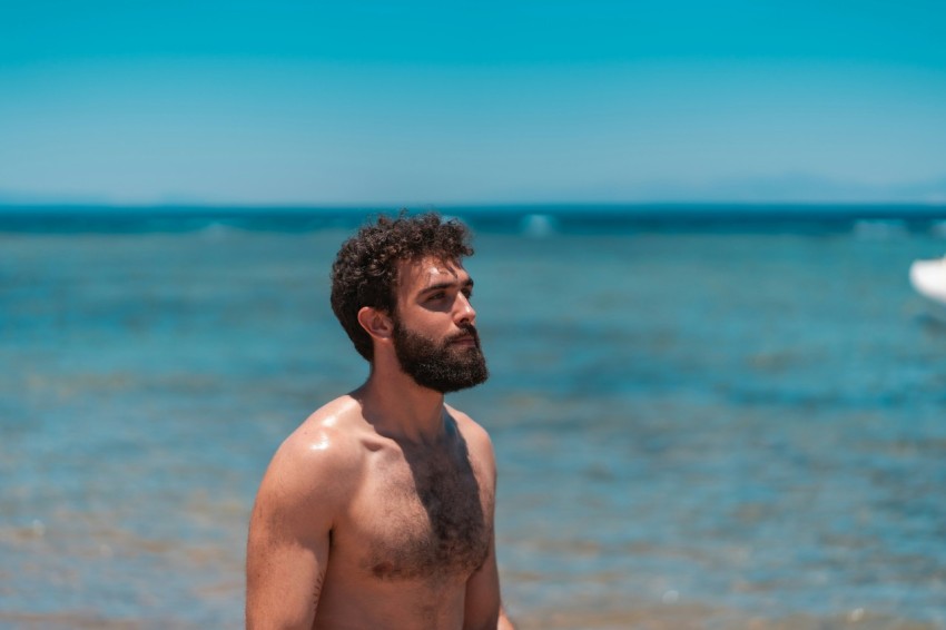 topless man standing near body of water during daytime