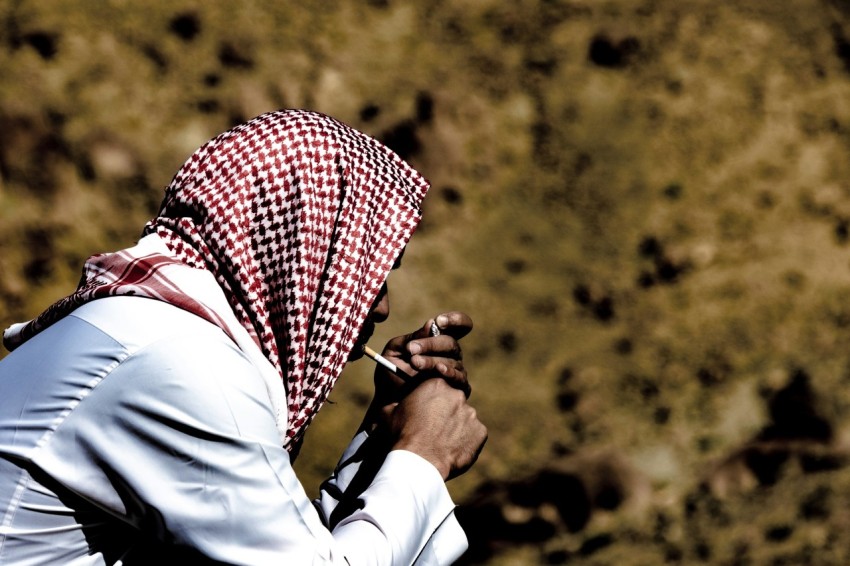 a person with a head covering is smoking a cigarette