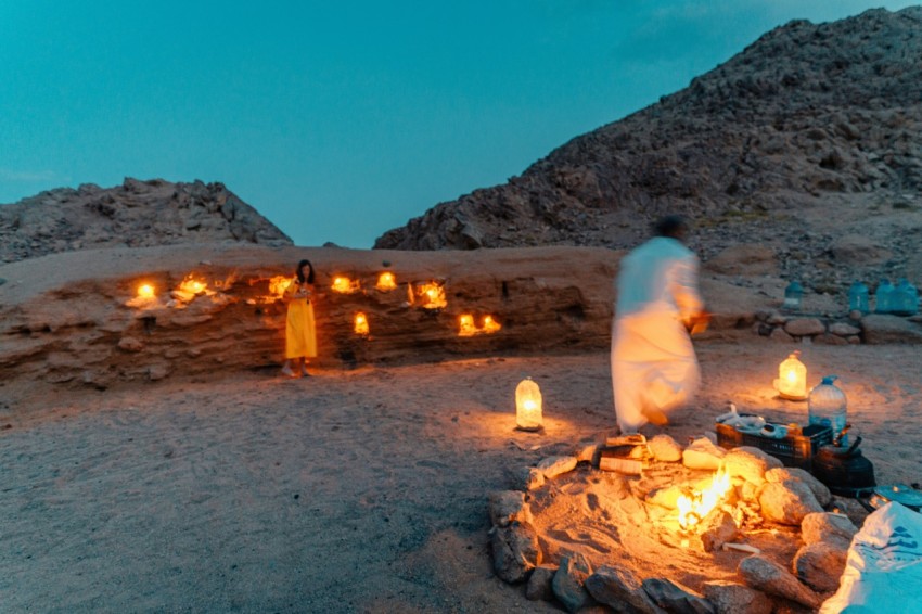 a man and woman standing next to a fire pit with a couple of candles in it