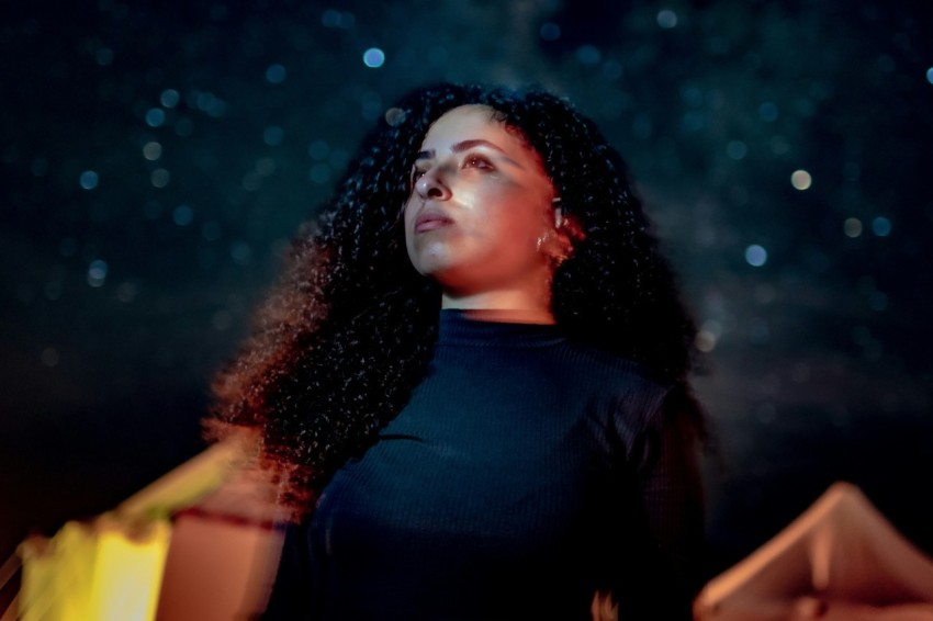 a woman standing in front of a sky filled with stars