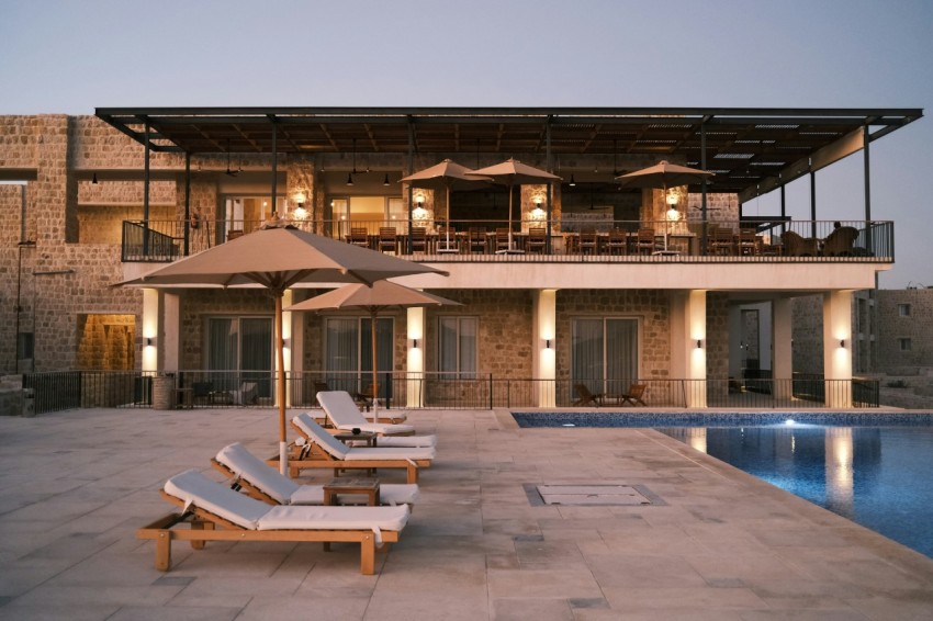 two lounge chairs and an umbrella near a swimming pool