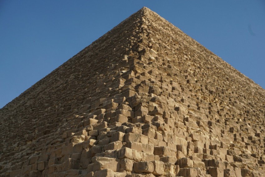 a stone pyramid with a blue sky with great pyramid of giza in the background