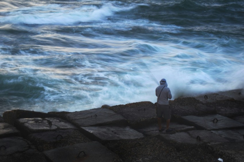 a man standing on the edge of a cliff next to the ocean