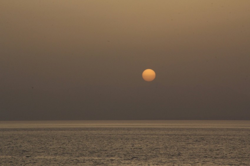 a large body of water with a sunset in the background