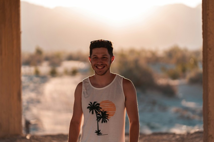 man in white tank top standing on beach during daytime